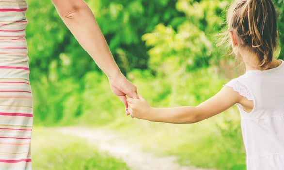 Mom and daughter are walking along the road holding hands. nature.
