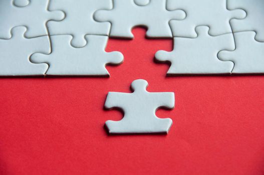 White jigsaw puzzle on red cover background with customizable space for text or idea. Copy space.