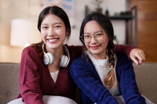 Two asian women having nice lively conversation in living room on sofa in cozy interior.