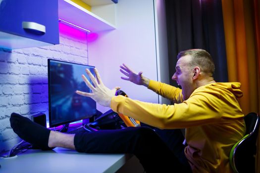 Male gamer playing racing games on the computer. He uses the steering wheel. Emotional game