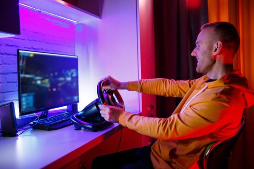 Male gamer playing racing games on the computer. He uses the steering wheel. Emotional game