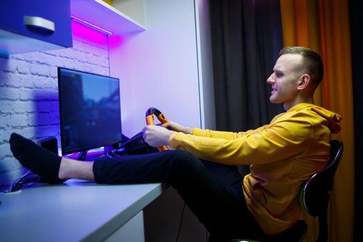 Male gamer playing racing games on the computer. He uses the steering wheel. Emotional game