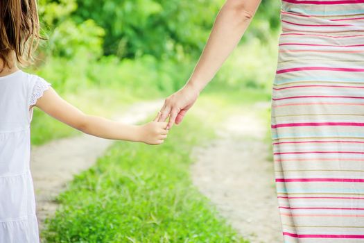 Mom and daughter are walking along the road holding hands. nature.