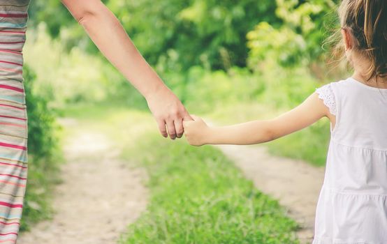 Mom and daughter are walking along the road holding hands. nature.