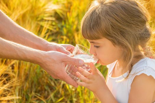 The father gives the child a glass of water. Selective focus.