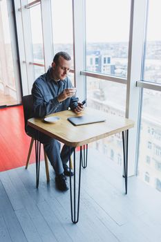 Happy smiling male manager sitting in cafe using mobile phone gadget, ordering delivery service via online app, free 4g wireless network in cafe, cheerful freelancer texting on mobile phone