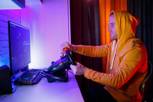 Male gamer playing racing games on the computer. He uses the steering wheel. Emotional game
