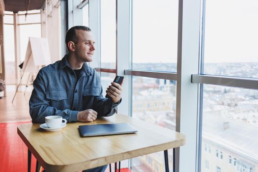 Happy smiling male manager sitting in cafe using mobile phone gadget, ordering delivery service via online app, free 4g wireless network in cafe, cheerful freelancer texting on mobile phone