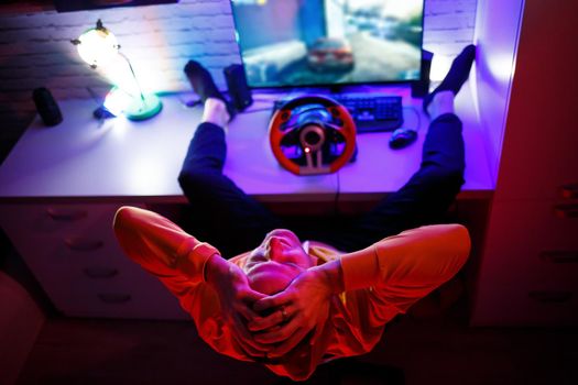 Male gamer playing racing games on the computer. He uses the steering wheel. Emotional game