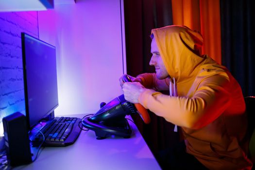 Male gamer playing racing games on the computer. He uses the steering wheel. Emotional game