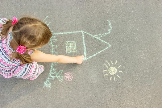 child draws a chalk house. Selective focus.