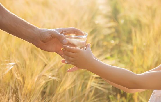 The father gives the child a glass of water. Selective focus.