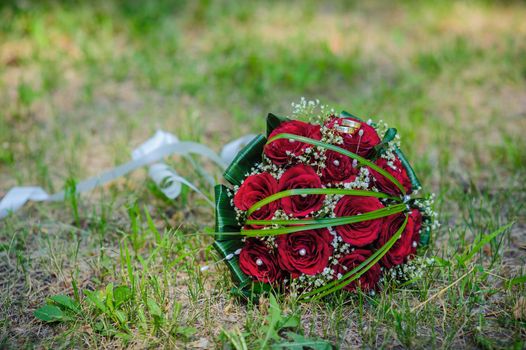 Bridal wedding bouquet of flowers. Wedding bouquet of red roses lying on a grass.