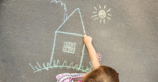 child draws a chalk house. Selective focus.