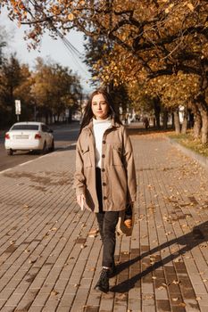 A stylish brunette woman walks around the autumn city. The season is autumn.