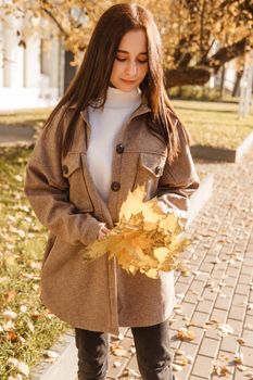 A stylish brunette woman walks around the autumn city. The season is autumn.