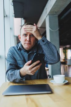 Excited young man in suit using mobile phone with funny expression, excited business man looking at his smartphone, reading good news via email, emotional lifestyle concept.