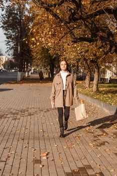 A stylish brunette woman walks around the autumn city. The season is autumn.