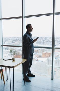 Young business man holding a phone. In an office or business center against the background of large windows of a skyscraper. Work and career, concept