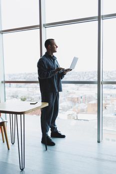 Young business man holding a phone. In an office or business center against the background of large windows of a skyscraper. Work and career, concept