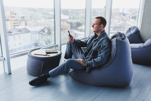 Confident male manager sitting in a modern workspace at a laptop and talking on the phone, remote work