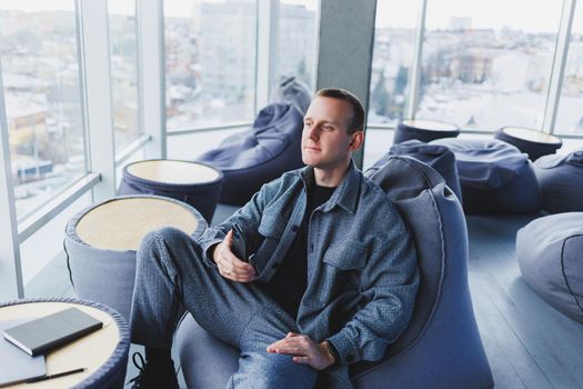 Confident male manager sitting in a modern workspace at a laptop and talking on the phone, remote work