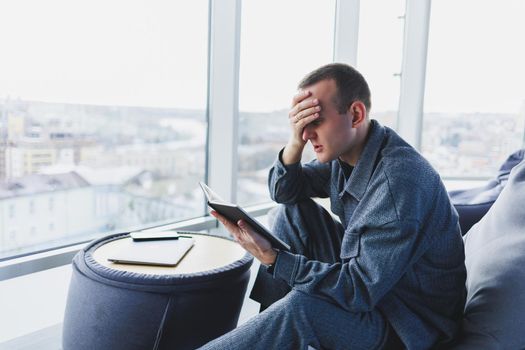 A male businessman in a casual suit resting in a comfortable pouf while working, an attractive freelancer in a suit works remotely and checks notes in a notebook