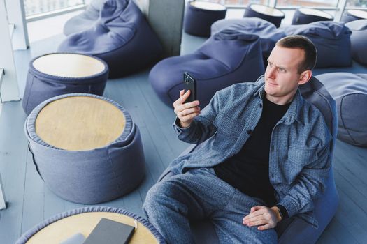 Excited young man in suit using mobile phone with funny expression, excited business man looking at his smartphone, reading good news via email, emotional lifestyle concept.