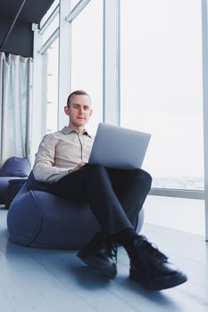 Young smart male businessman is sitting in the office and working on a project related to public cyber technology. Businessmen with laptop trying to meet deadlines in external marketing.
