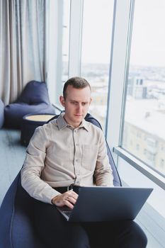 Young smart male businessman is sitting in the office and working on a project related to public cyber technology. Businessmen with laptop trying to meet deadlines in external marketing.