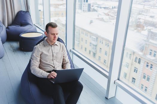 A successful businessman sits in a working cafe and works on an important project. Businessman is typing on a laptop. Businessman using laptop in cafe