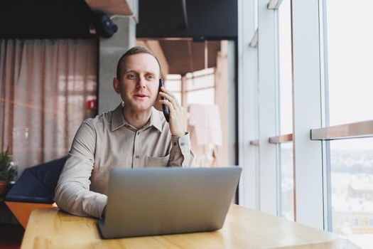 A successful businessman sits in a working cafe and works on an important project. Businessman is typing on a laptop. Businessman using laptop in cafe