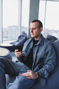 Confident male manager sitting in a modern workspace at a laptop and talking on the phone, remote work