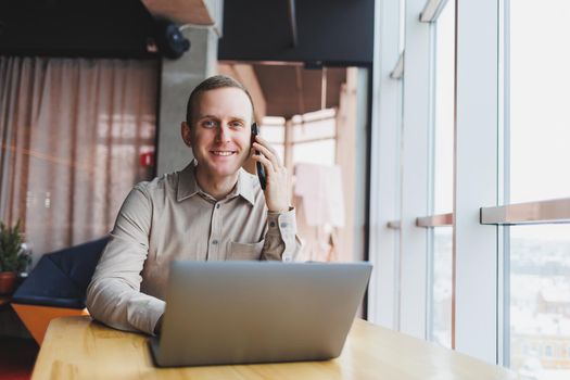 A successful businessman sits in a working cafe and works on an important project. Businessman is typing on a laptop. Businessman using laptop in cafe