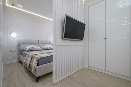 Studio apartment interior with living room and bedroom with double bed, white walls and light fixture