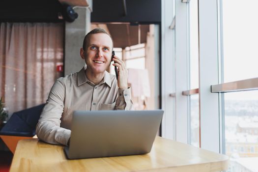 A successful businessman sits in a working cafe and works on an important project. Businessman is typing on a laptop. Businessman using laptop in cafe