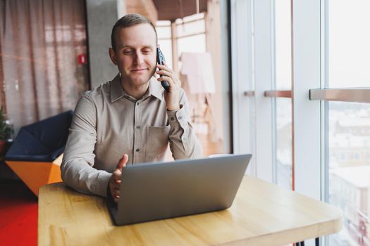 A successful businessman sits in a working cafe and works on an important project. Businessman is typing on a laptop. Businessman using laptop in cafe