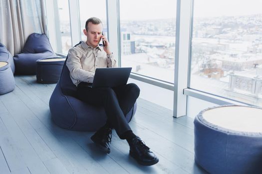 Young smart male businessman is sitting in the office and working on a project related to public cyber technology. Businessmen with laptop trying to meet deadlines in external marketing.