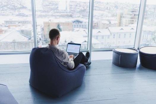 Young smart male businessman is sitting in the office and working on a project related to public cyber technology. Businessmen with laptop trying to meet deadlines in external marketing.