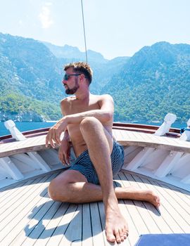 young man relaxing on a wooden boat during a boat trip to Butterfly beach at Fethiye Turkey, Tanning a young boy in swimwear