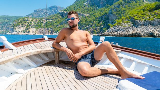 young man relaxing on a wooden boat during a boat trip to Butterfly beach at Fethiye Turkey, Tanning a young boy in swimwear