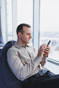 A businessman communicates with his clients by phone while sitting in a modern office workspace. Focused businessman sits alone in a modern workspace.