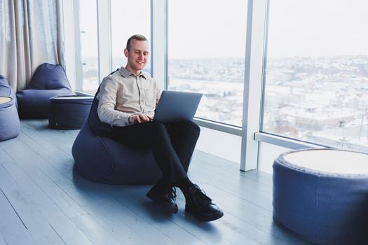 A successful businessman sits in a working cafe and works on an important project. Businessman is typing on a laptop. Businessman using laptop in cafe