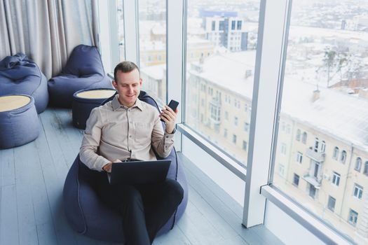 A successful businessman sits in a working cafe and works on an important project. Businessman is typing on a laptop. Businessman using laptop in cafe