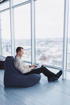 Young smart male businessman is sitting in the office and working on a project related to public cyber technology. Businessmen with laptop trying to meet deadlines in external marketing.