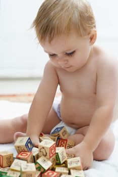 Showing interest in educational games. A baby playing with his building blocks looking content