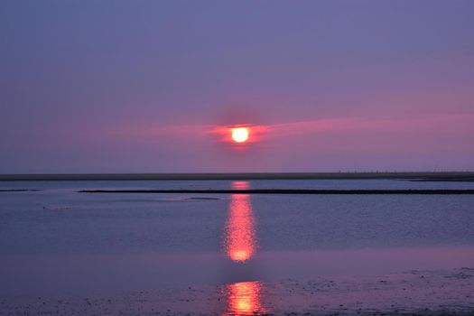 Sunset at a beach at the North Sea with reflexion on the water