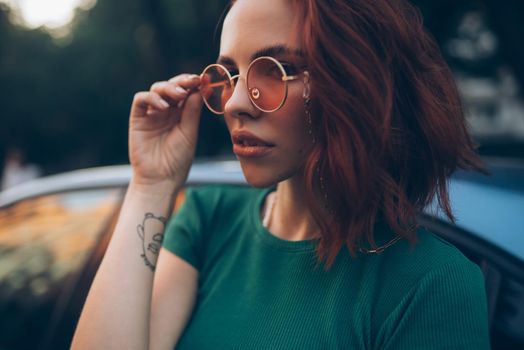 Young woman in glasses posing near car