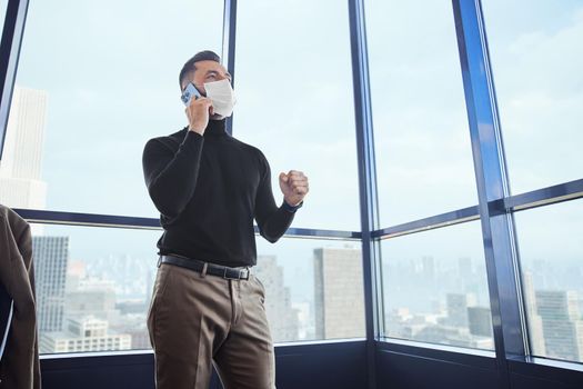 happy business man with a smartphone standing near the window. close-up.