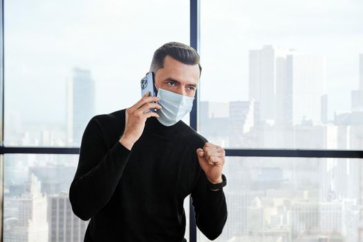 emotional businessman in a protective mask talking on a smartphone. close-up.